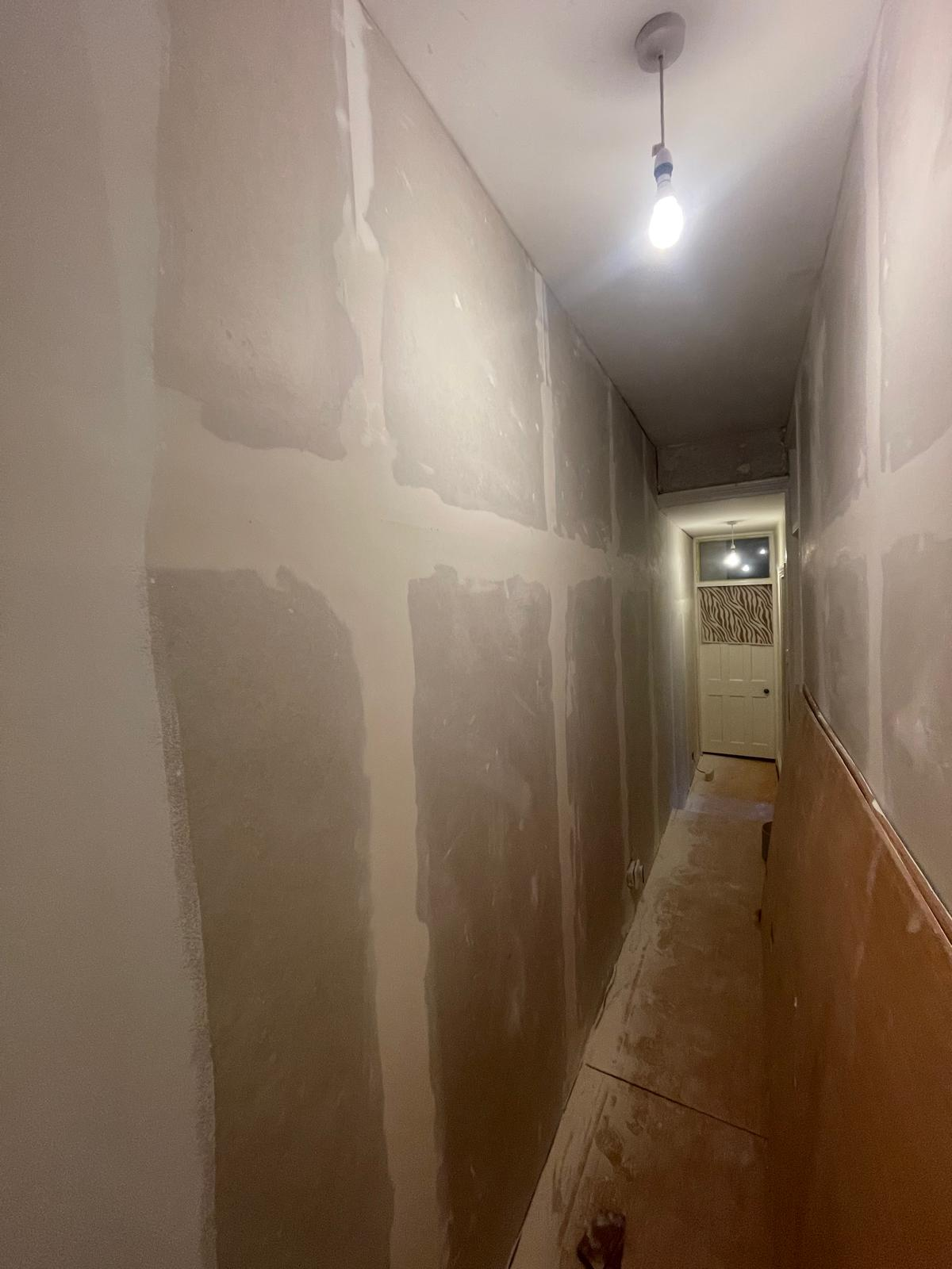 Long hallway during skim coating and preparation before flooring and wall panelling installation
