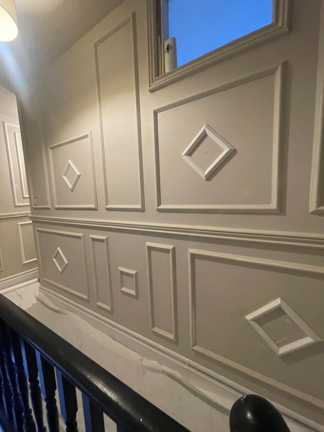 Close-up of finished wall moulding detail and decorative diamond panel inserts on the landing