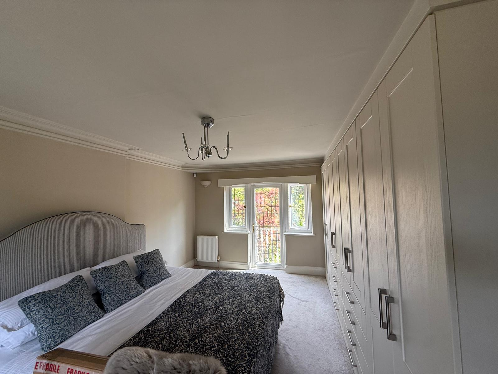 Finished bedroom showing bespoke fitted wardrobes alongside redecorated walls