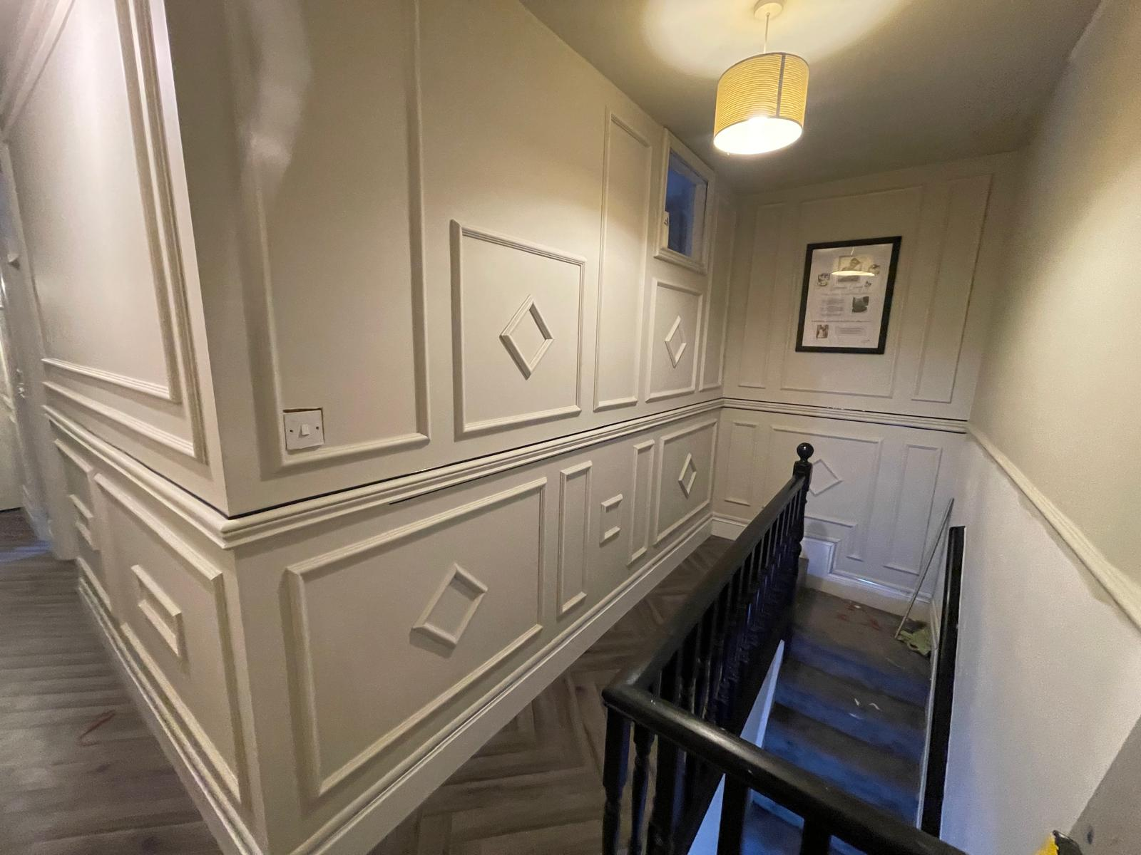 Upper landing finished with decorative wall mouldings, framed artwork and staircase detail