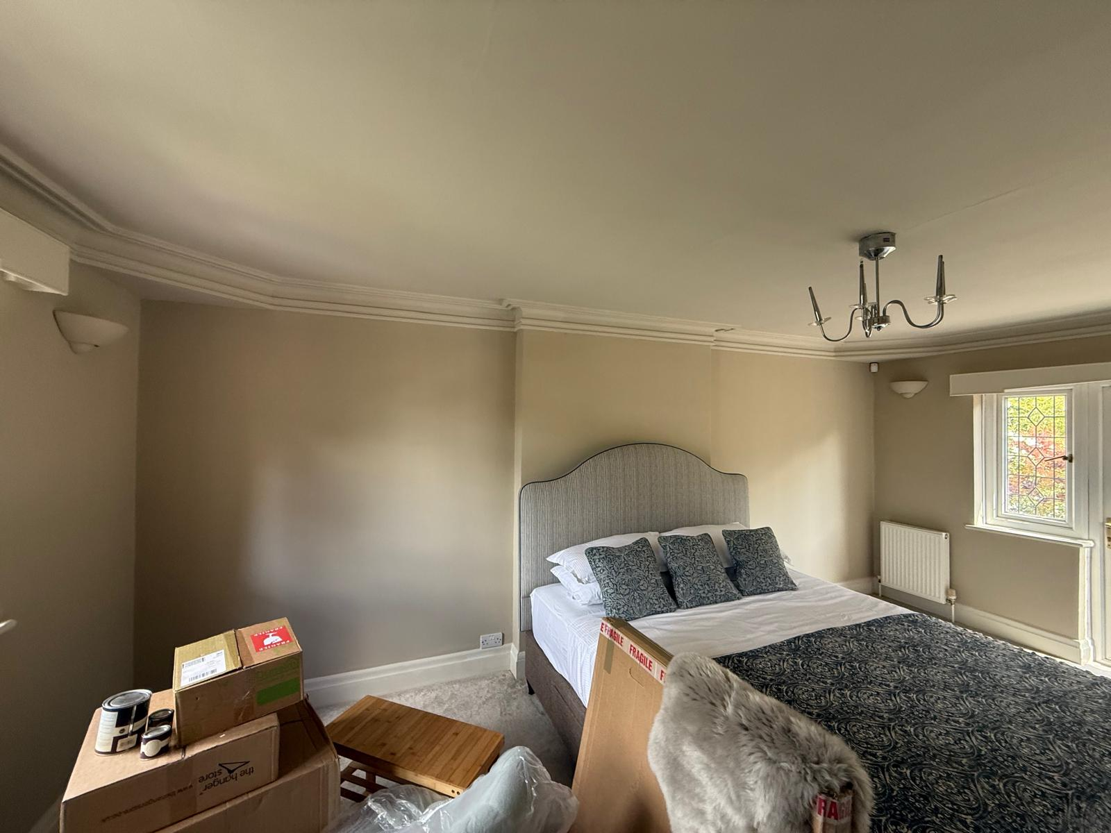 Completed bedroom with warm neutral walls and restored decorative coving