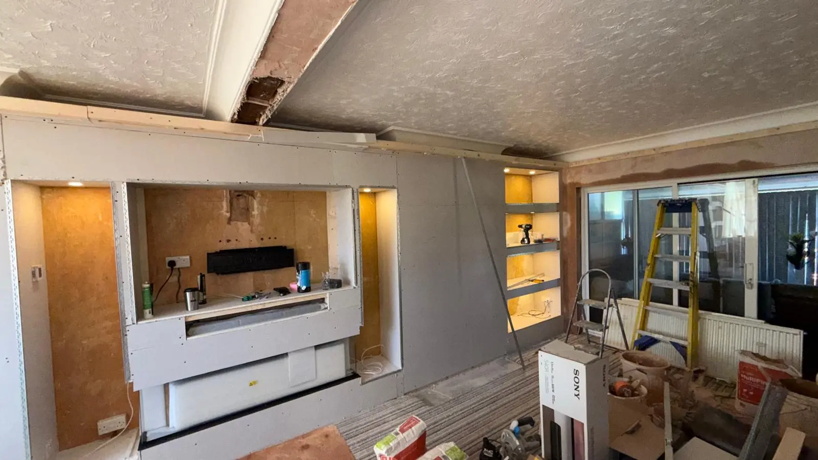 Media wall boarding with recessed shelves and warm lighting first fix
