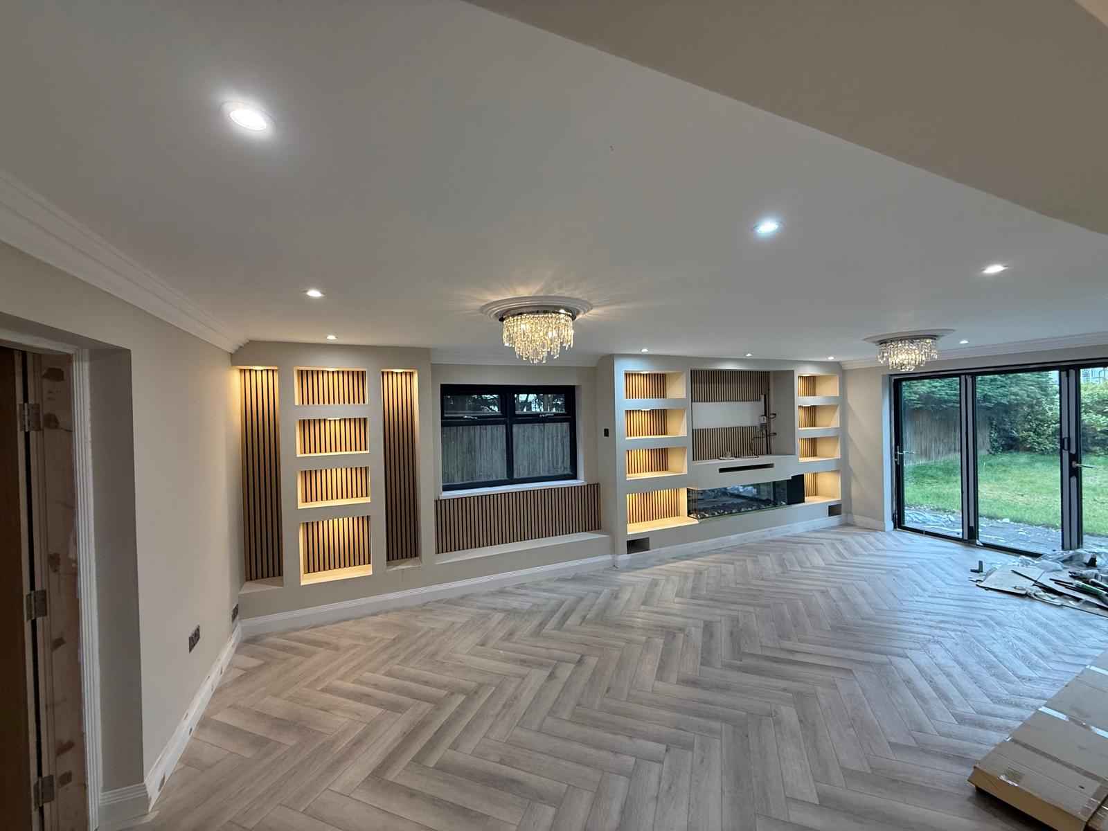 Completed open-plan lounge with bespoke media wall, fluted panelling and herringbone floor