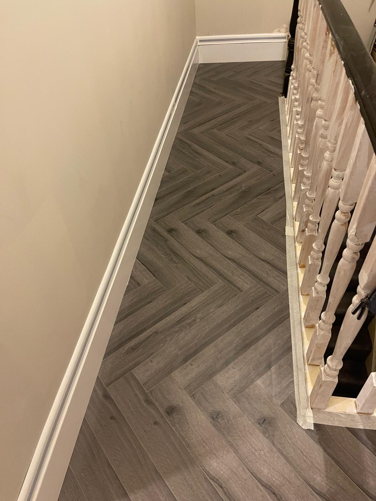 Landing detail showing newly installed herringbone flooring beside the staircase