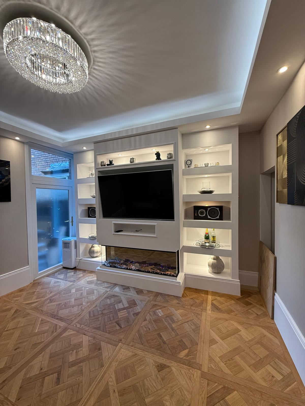 Finished media wall with integrated lighting, shelving, and fireplace