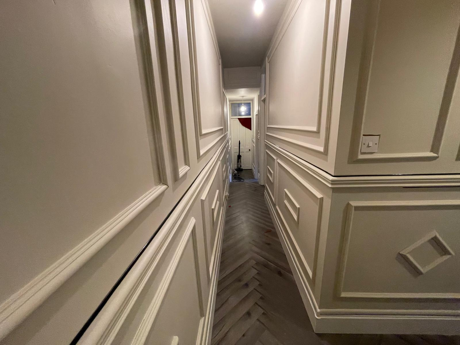 Perspective view through a finished panelled hallway with refined trim and patterned floor