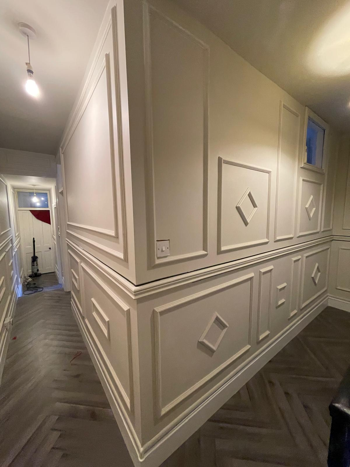 Finished hallway corner with decorative wall mouldings and herringbone flooring