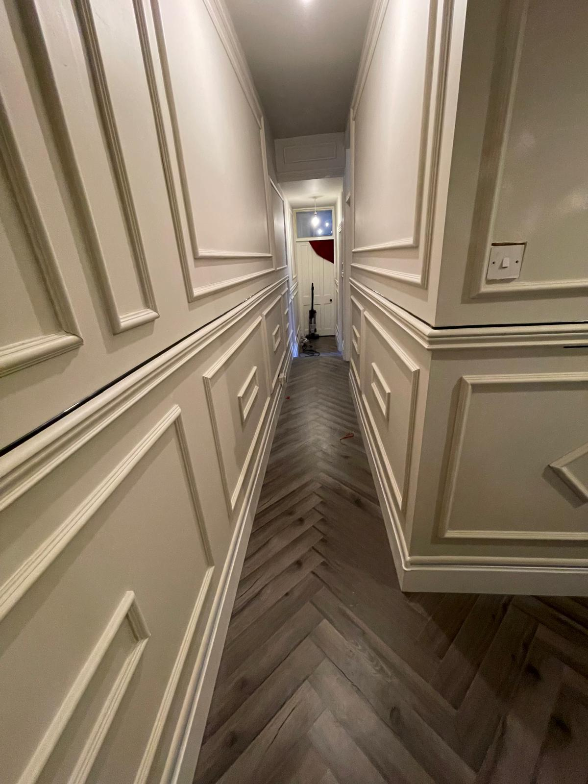 Finished hallway with full wall panelling details and herringbone floor running through the corridor