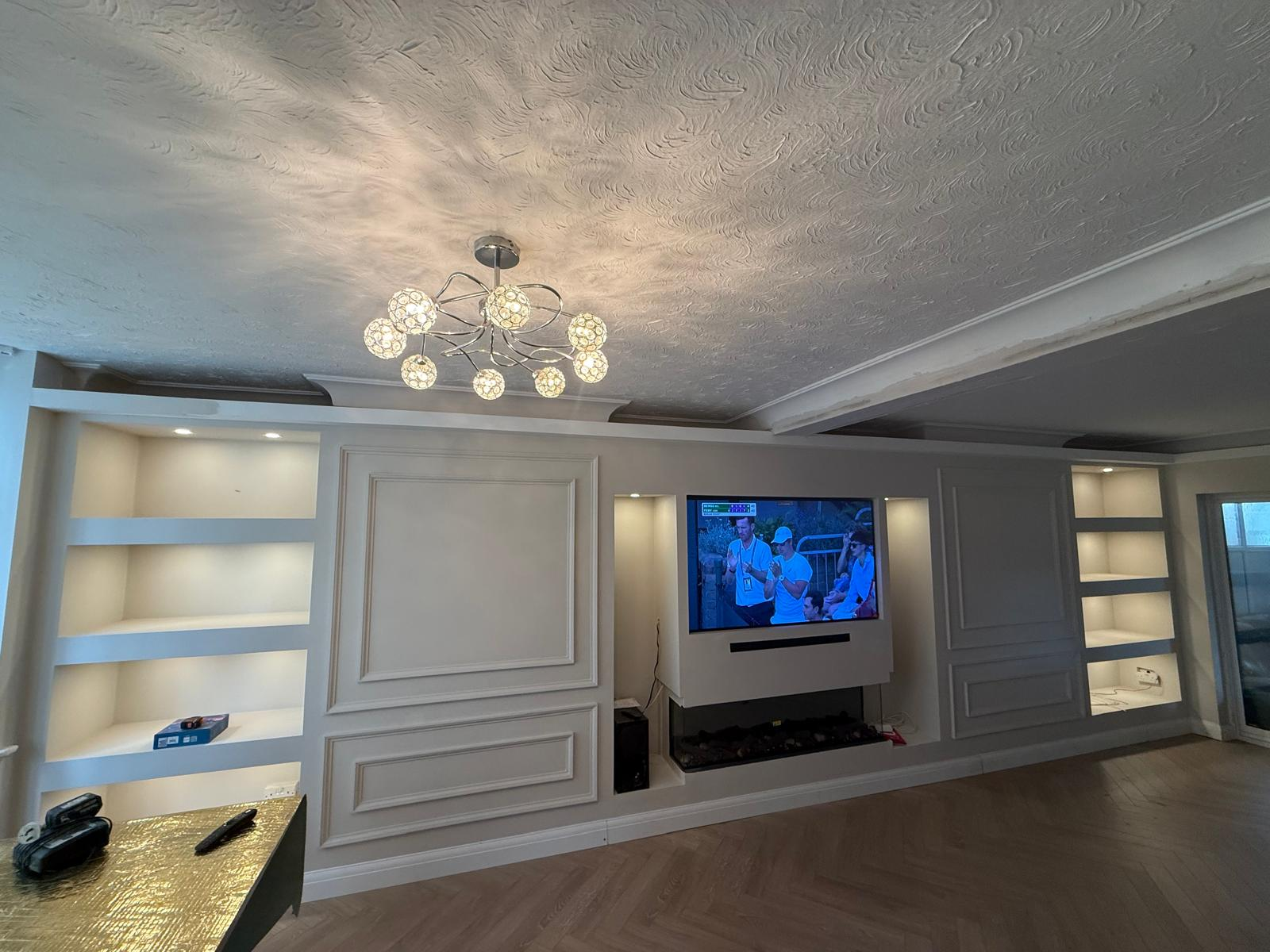 Finished media wall with moulded panelling, lit alcove shelving and inset fire