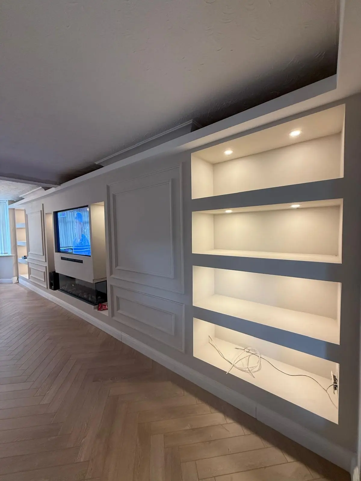 Completed media wall with backlit recessed shelving and moulded panelling