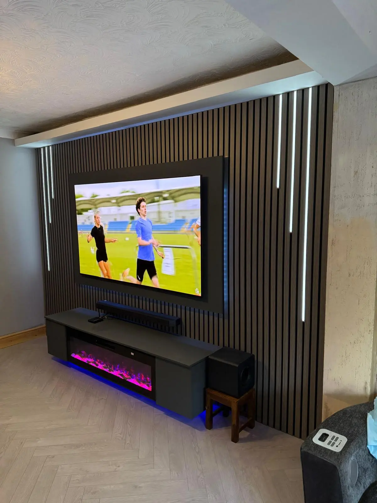 Angled view of the finished slat media wall with recessed lighting and sound system
