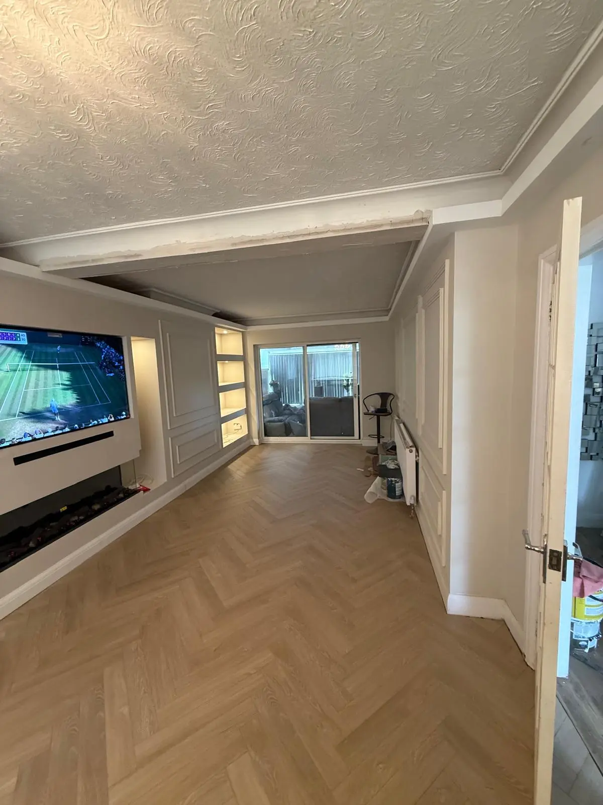 Wide view of finished lounge with media wall, panelling and herringbone flooring