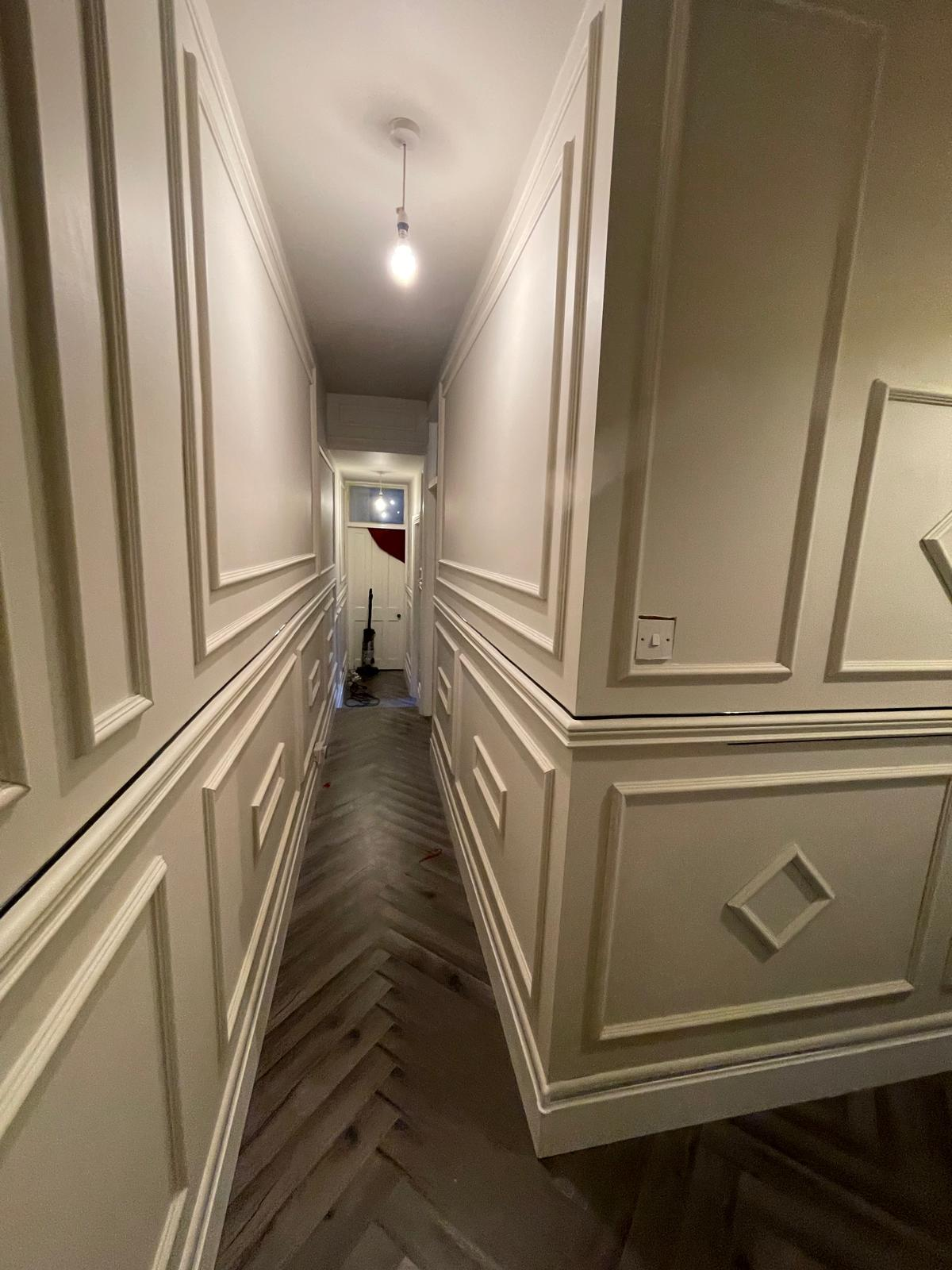 Finished hallway with decorative wall panelling under simple overhead lighting